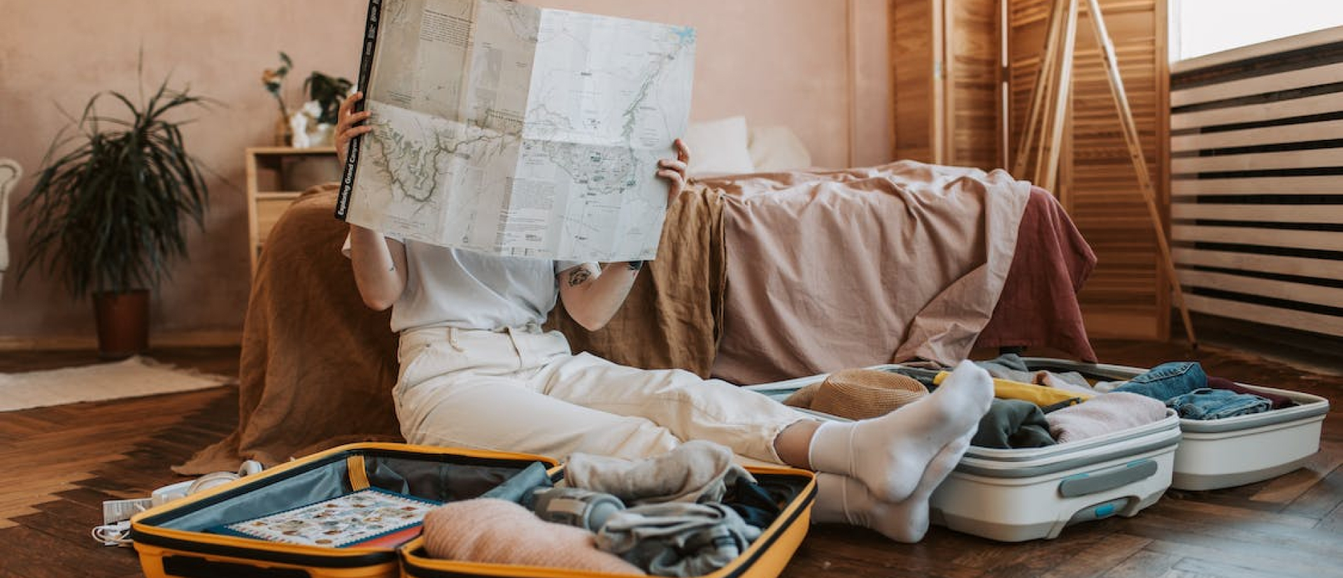 Girl sitting on floor beside open suitcases and reading a map