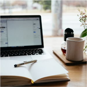 Laptop with notepad, pen and coffee mug