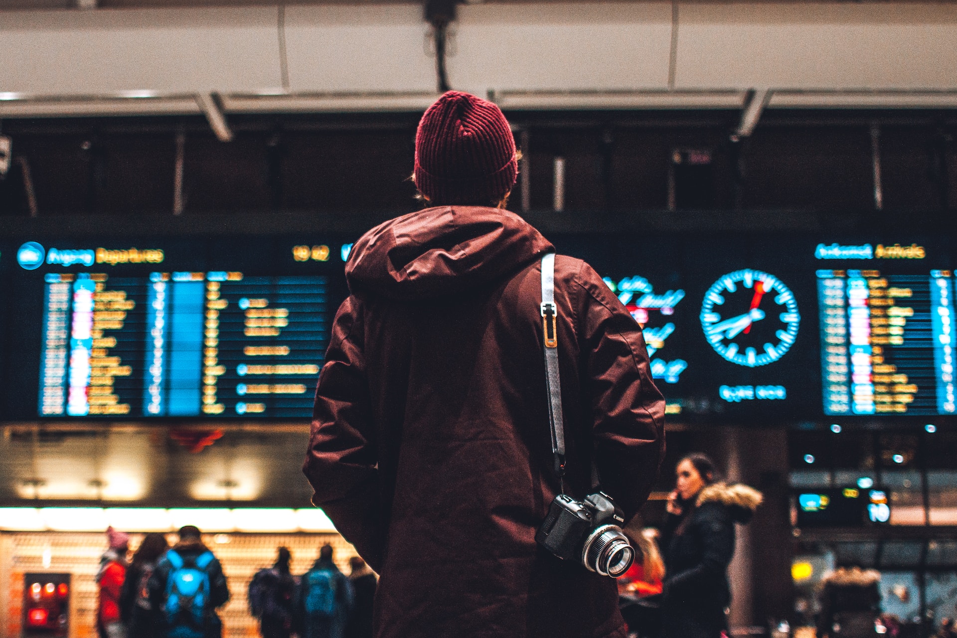 Man carrying camera looking at train departure times