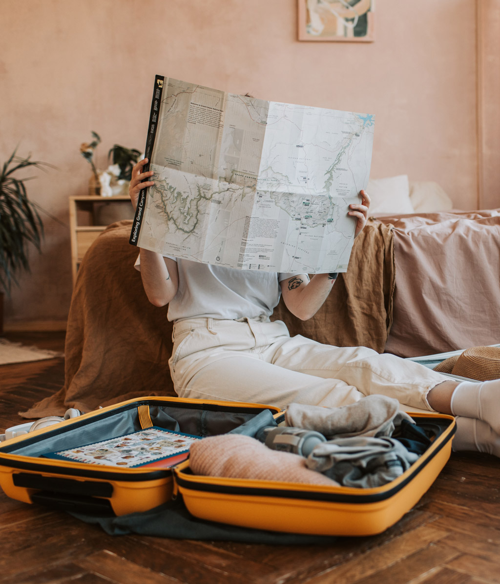 Girl sitting on floor beside open suitcases and reading a map